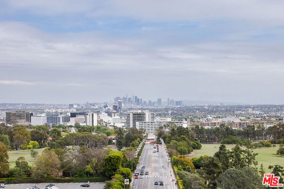 Wide angle view of a cityscape with buildings and roads under a cloudy sky.