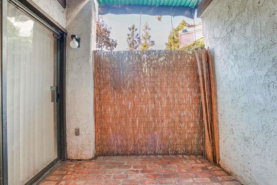 Small outdoor area with brick flooring and bamboo fencing.