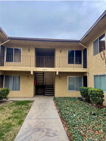 Front view of a two-story apartment building with an open walkway and stairway.
