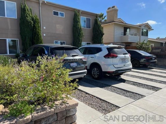 Outdoor parking area in front of a residential building with multiple parked cars.