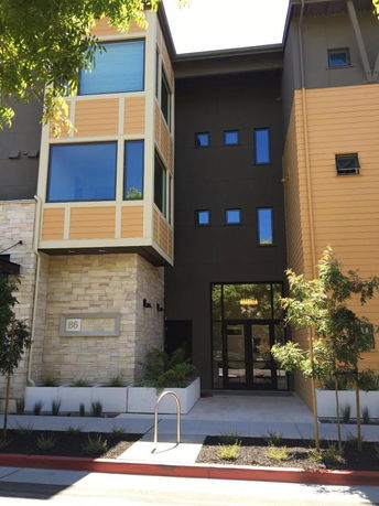 Front view of a modern multi-story building with a mix of stone and siding exterior.