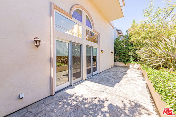 Front view of a house with large glass doors and arched windows.