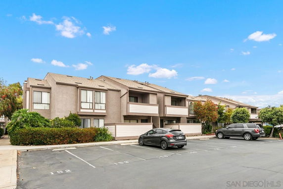 Front view of a two-story apartment complex with parking spaces in front.