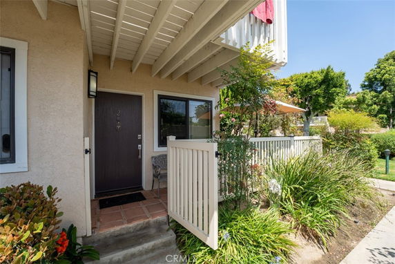 Front view of a beige house entrance with a small patio and plants.