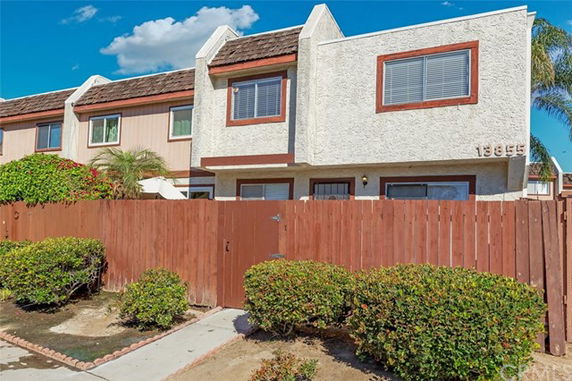 Front view of a two-story townhouse with a wooden fence.