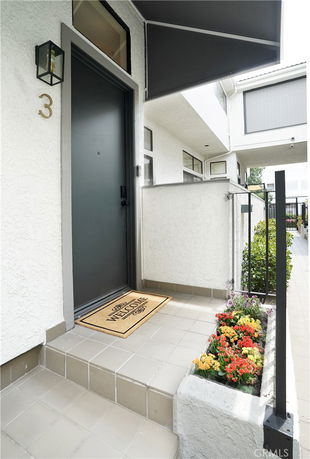 Front entrance of a house with a black door and a welcome mat.