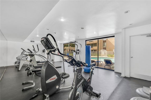 Indoor gym area with exercise bikes and a view of the pool outside.