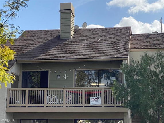 Front view of a two-story house with a balcony and chimney.