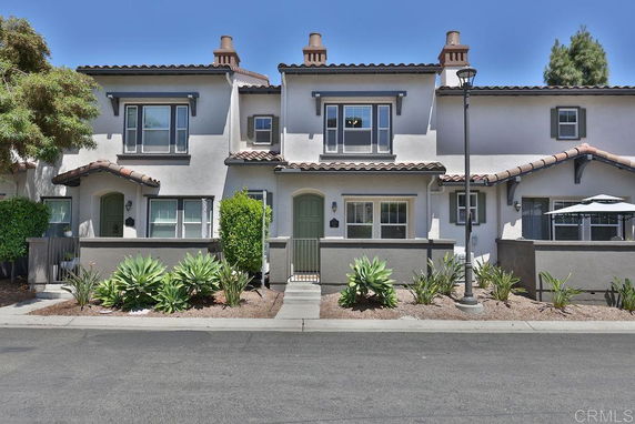 Front view of a two-story townhouse with a tiled roof and small garden in front.