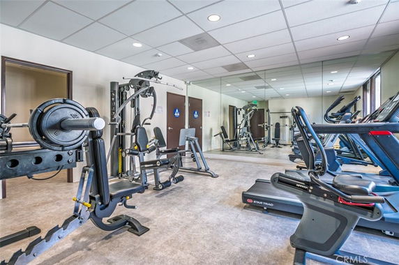 Room with gym equipment including treadmills and weight machines.