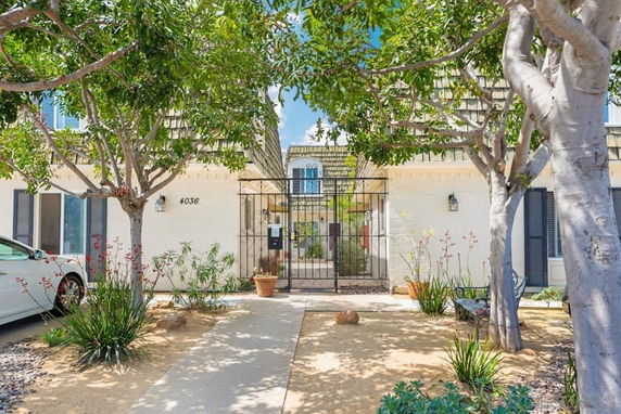 Front view of a house with a gated entrance and trees.