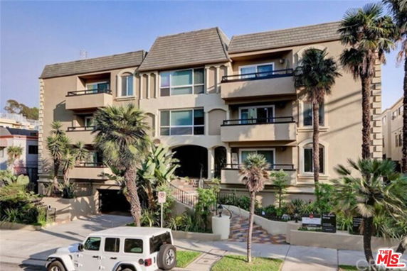 Front view of a multi-story residential building with balconies and a tiled entrance.