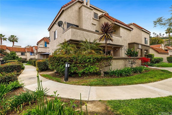 Front view of a multi-story residential building with a red-tiled roof and landscaped surroundings.