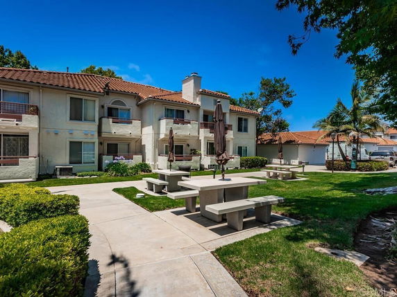 Front view of a residential apartment building with balconies and a tiled roof.
