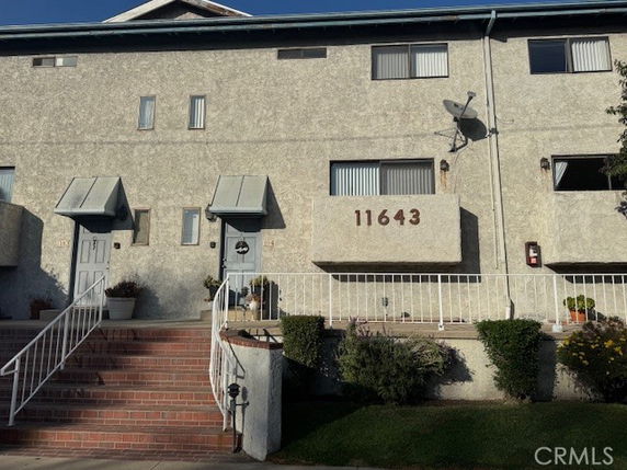 Front view of a two-story townhouse with brick steps and a metal railing.