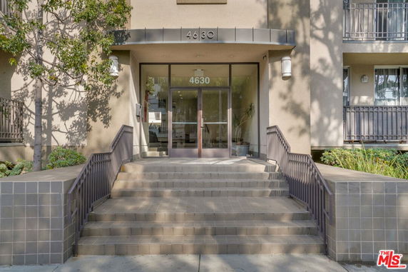 Front view of a building entrance with stairs and glass doors.