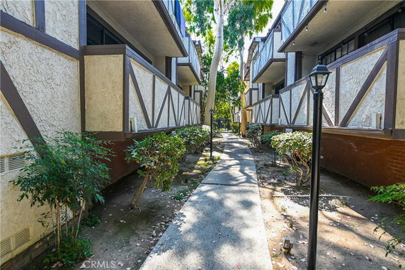 Exterior view of a multi-story building with balconies and a walkway between structures.