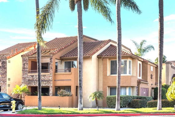 Front view of a two-story house with a stucco exterior and a terracotta roof.