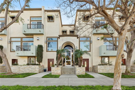 Front view of a multi-story residential building with balconies and a central entrance.