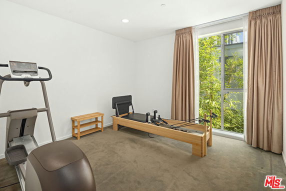 Room with exercise equipment including a treadmill and a pilates reformer.