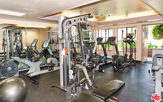 Indoor gym area with various exercise equipment including treadmills, weight machines, and exercise balls.