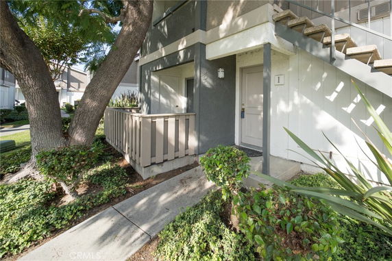 Front view of a multi-story building entrance with a stairway and small porch.