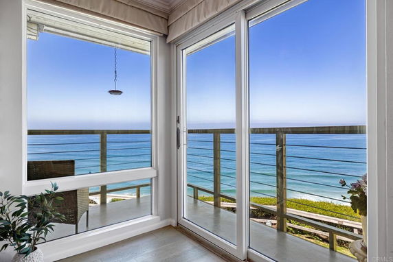 Wide angle view of the ocean from a balcony with glass doors.
