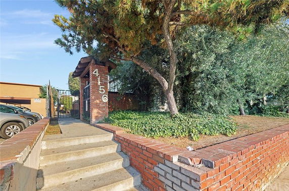 Front view of a brick entryway with steps leading up to a gated entrance.