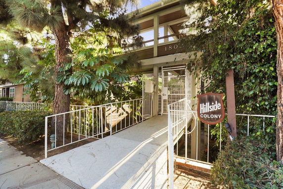 Front view of a building entrance with a ramp and greenery.