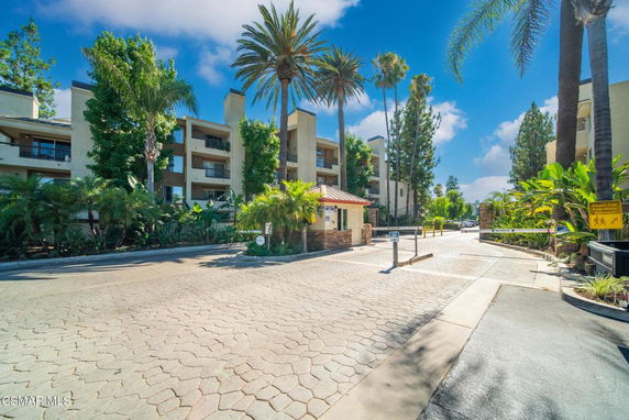 Front view of a multi-story residential building with balconies and surrounding palm trees.