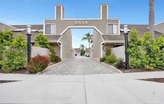Front view of a building with a large archway and unit numbers displayed.