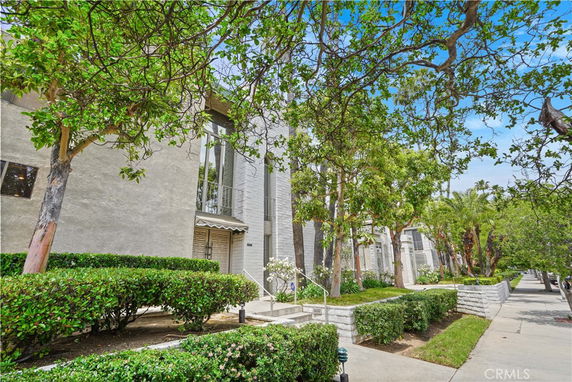 Front view of a modern multi-story building with large windows and landscaped shrubbery.