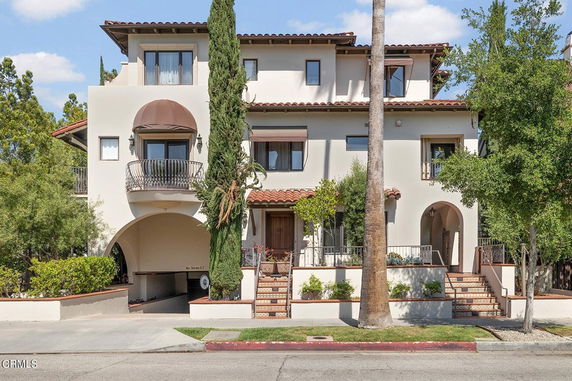 Front view of a multi-story house with arched entryways and balconies.
