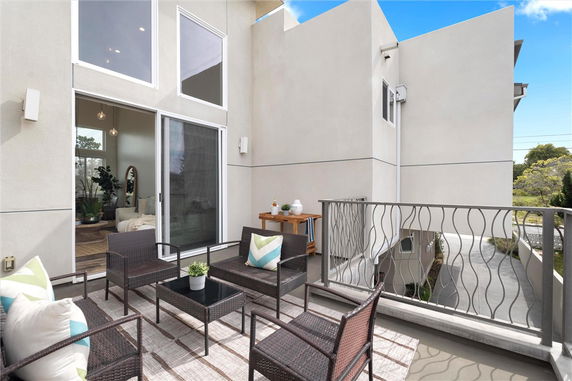 Balcony view with outdoor seating and railing overlooking surrounding areas.