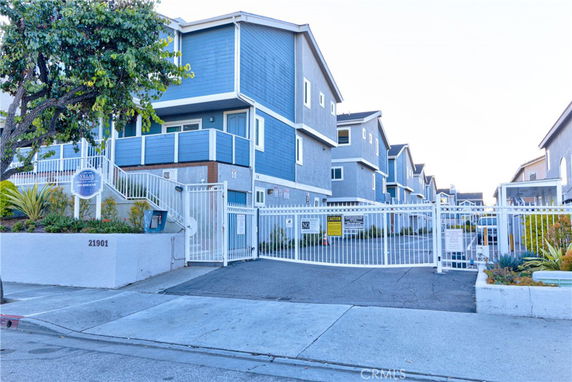 Front view of a multi-story residential building with blue and gray exterior and gated entry.