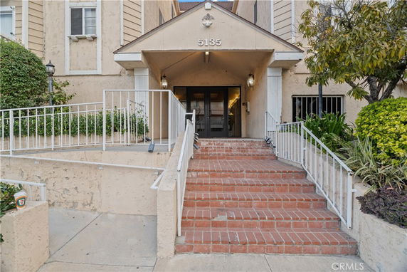Front view of a building entrance with stairs and railing.