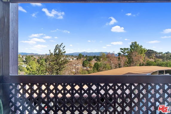Wide view of natural surroundings seen through a lattice fence from a building.