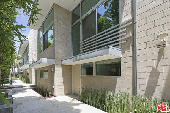 Front view of a modern multi-story building with large windows and a pathway.