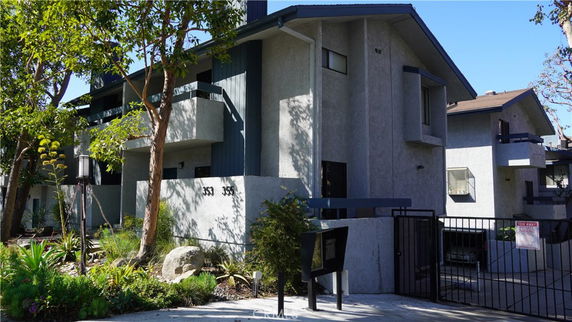 Front view of a multi-story residential building with balconies and a gated entrance.