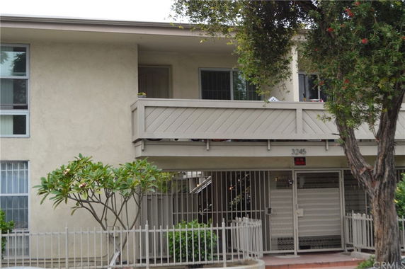 Front view of a two-story building with a balcony and gated entrance.