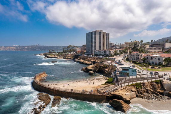 Coastal panoramic view with buildings near the shore and a visible segment of the ocean.