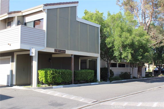 Front view of a multi-story building with flat roof and siding panels.