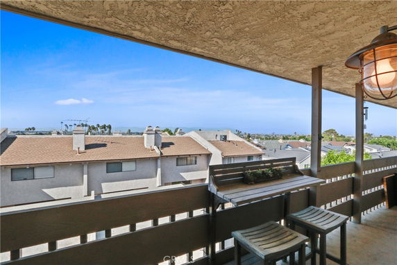 Panoramic view from a balcony overlooking neighboring rooftops and distant hills.