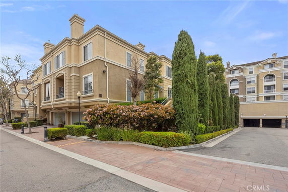 Front view of a multi-story building with symmetrical facade and tall cypress trees lining the entrance.