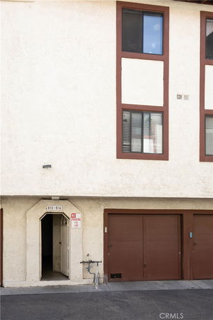 Front view of a multi-story building with garage doors and an open entrance.