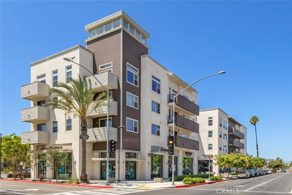 Front view of a modern multi-story building with balconies and a commercial ground floor.