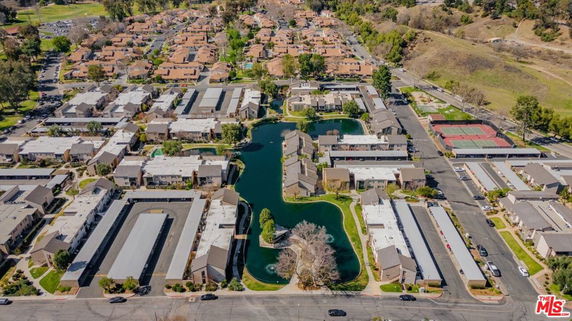 Aerial panoramic view of a residential complex with multiple buildings, roads, and landscaped areas with water features.