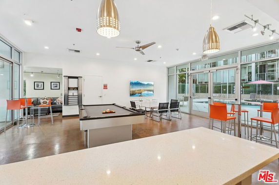 Recreation room with a pool table, seating area, and large windows.