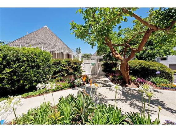 Front view of a house with a steep roof and a garden path leading to a gated entrance.