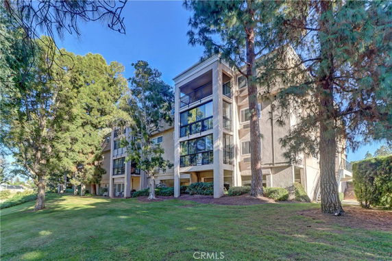 Front view of a multi-story building with large windows surrounded by trees.